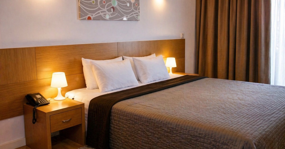 Standard guest room with king-size bed, warm bedside lighting, and abstract artwork above the headboard