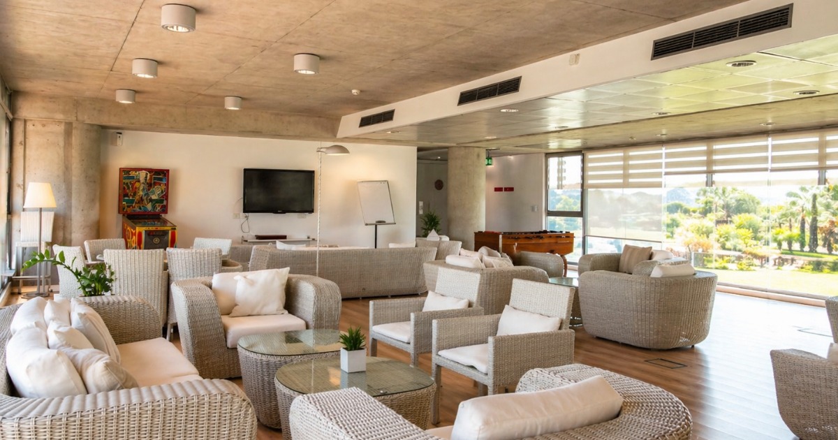 Residence lounge and common area with wicker seating, TV, and large windows overlooking the gardens