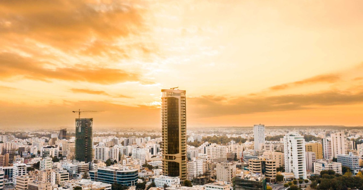 Nicosia modern skyline at golden hour featuring high-rise towers silhouetted against a dramatic orange sunset sky